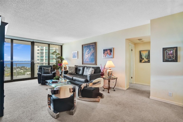 living room with a water view, a wall of windows, light colored carpet, and a textured ceiling