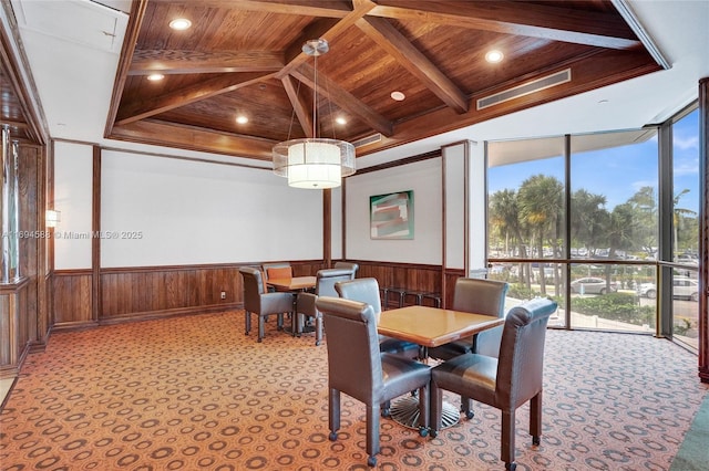 dining room with beam ceiling, light carpet, and wooden ceiling