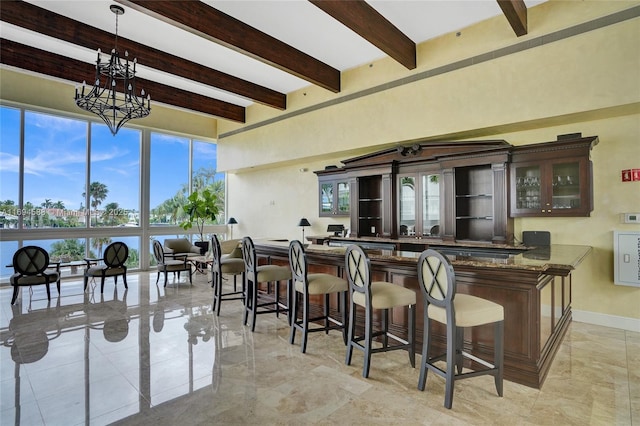 bar with dark stone counters, beam ceiling, a chandelier, and hanging light fixtures