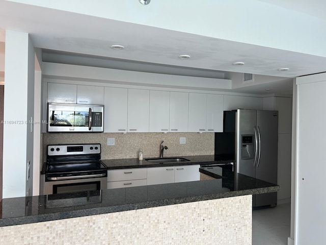 kitchen with backsplash, dark stone counters, stainless steel appliances, sink, and white cabinets