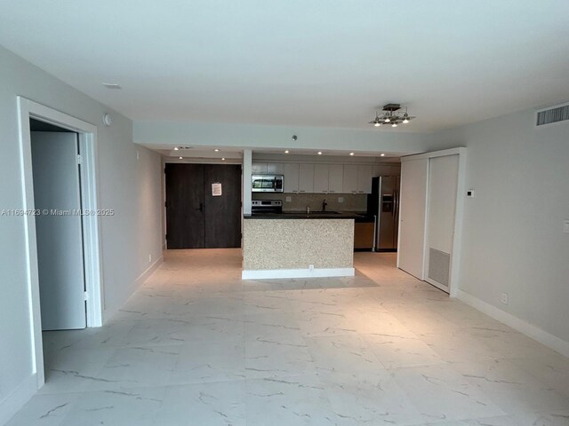 kitchen featuring decorative backsplash, a center island, sink, and stainless steel appliances