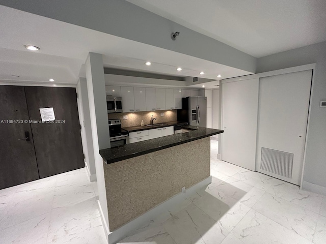 kitchen featuring decorative backsplash, stainless steel appliances, sink, a center island, and white cabinetry