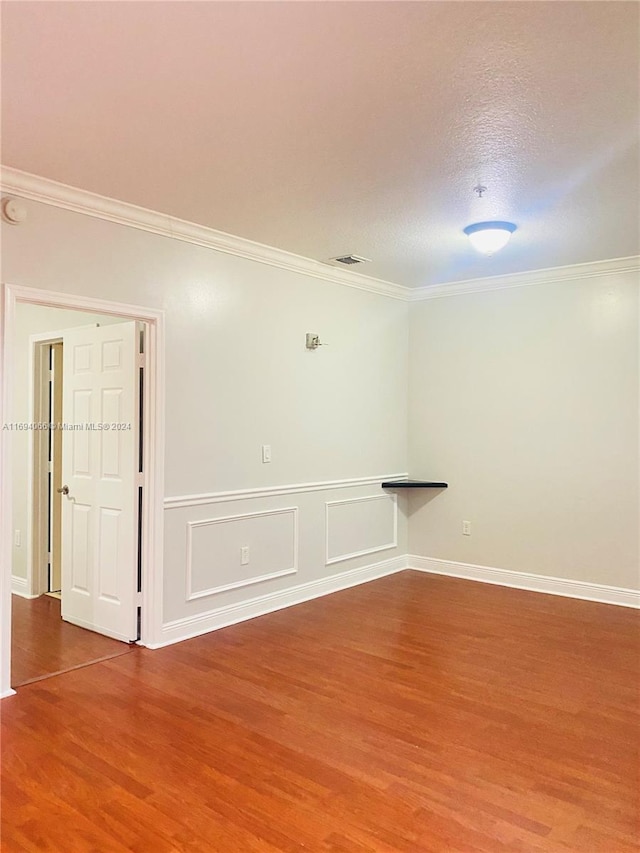 unfurnished room with a textured ceiling, hardwood / wood-style flooring, and ornamental molding