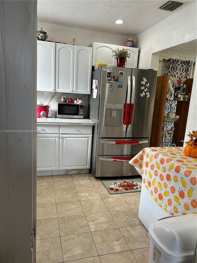 kitchen featuring white cabinets, light tile patterned floors, and appliances with stainless steel finishes