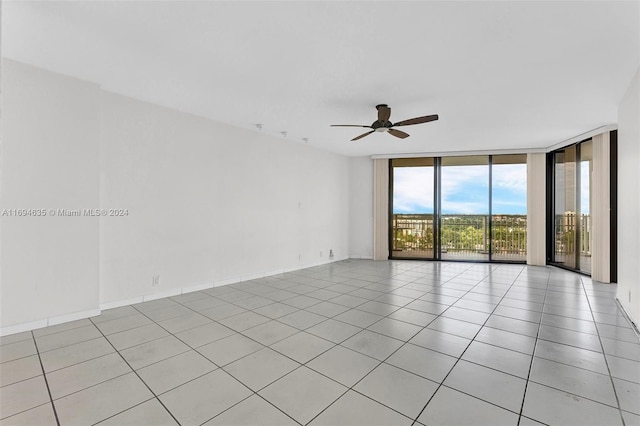 tiled empty room featuring ceiling fan and expansive windows