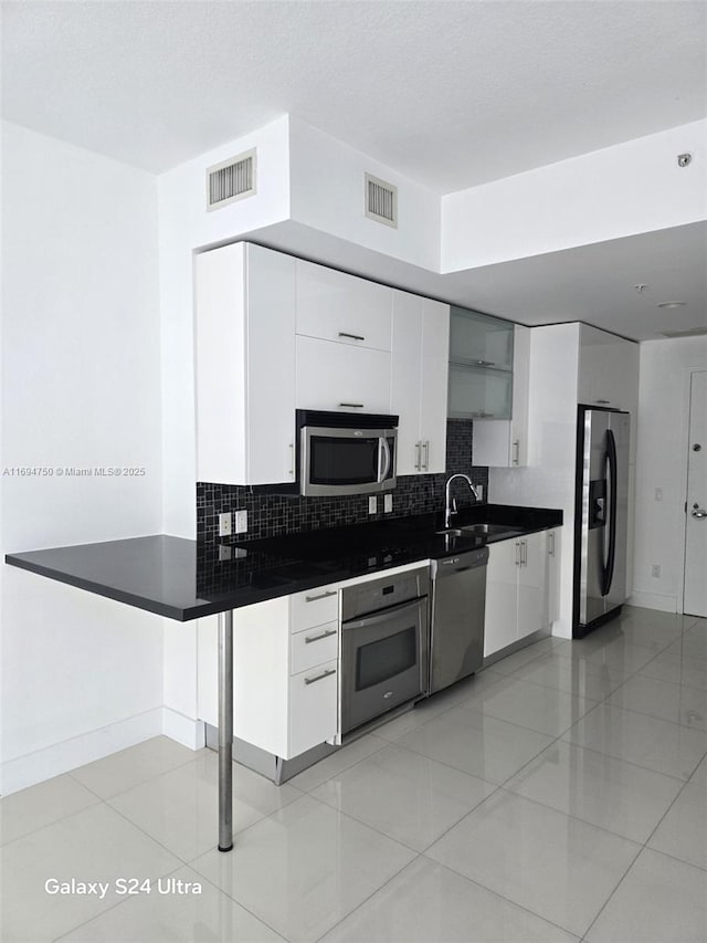 kitchen featuring dark countertops, visible vents, backsplash, and appliances with stainless steel finishes