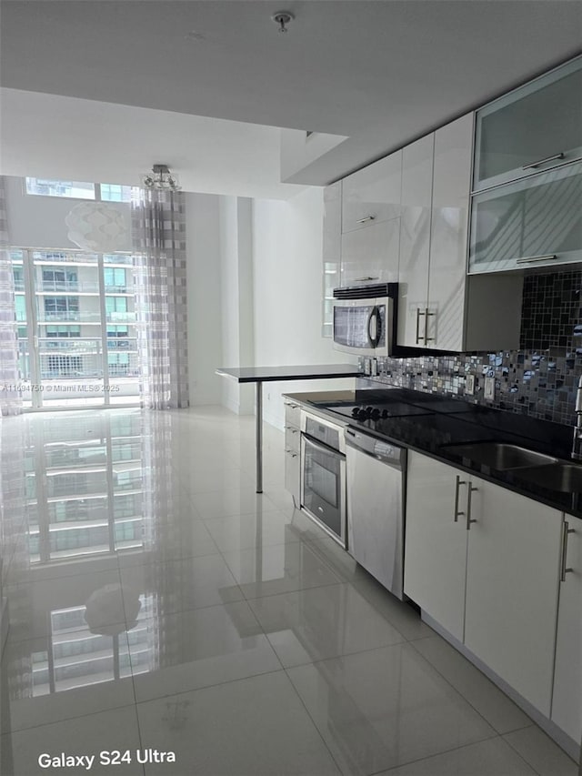 kitchen featuring decorative backsplash, appliances with stainless steel finishes, white cabinetry, and a sink