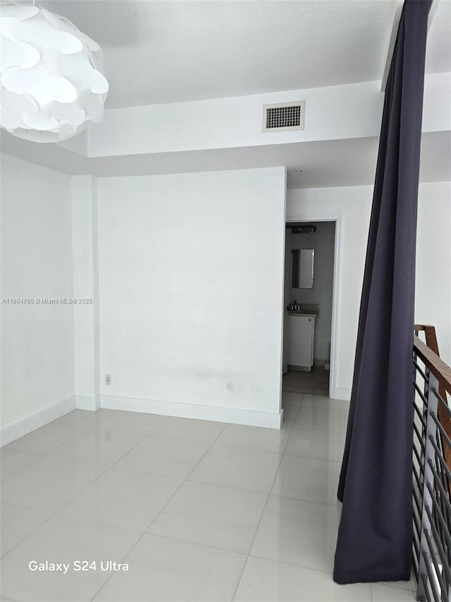 unfurnished room featuring light tile patterned floors, baseboards, and visible vents