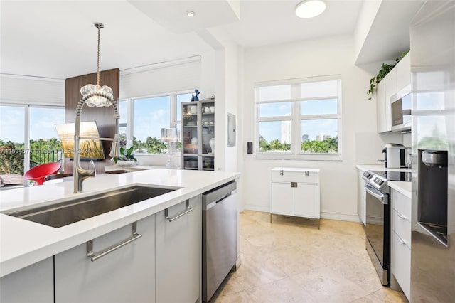 kitchen featuring a wealth of natural light, white cabinetry, hanging light fixtures, and stainless steel appliances