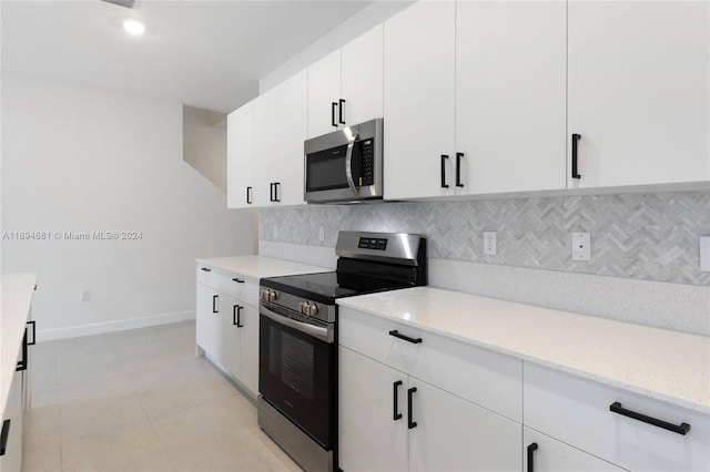 kitchen with white cabinetry, light stone countertops, backsplash, light tile patterned floors, and appliances with stainless steel finishes