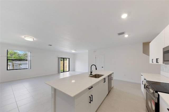 kitchen featuring white cabinetry, a kitchen island with sink, a healthy amount of sunlight, and sink