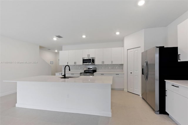 kitchen featuring white cabinetry, sink, a kitchen island with sink, decorative backsplash, and appliances with stainless steel finishes