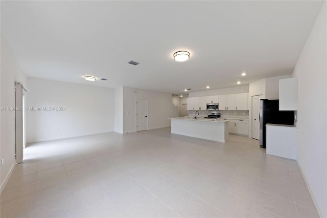 kitchen featuring white cabinetry, stainless steel appliances, backsplash, a center island with sink, and light tile patterned floors