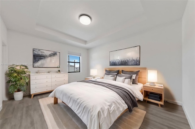 bedroom with a raised ceiling and dark wood-type flooring