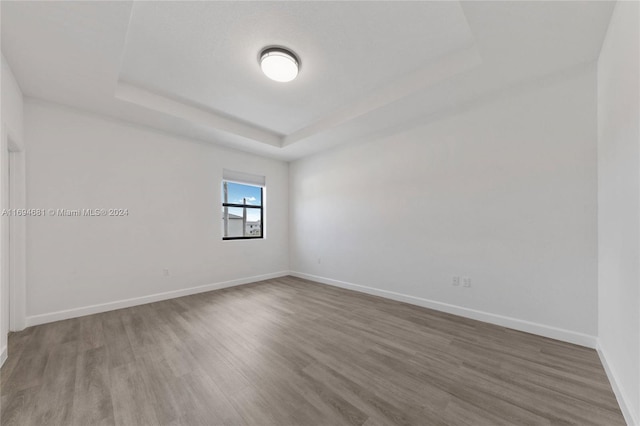 empty room with a raised ceiling and hardwood / wood-style floors