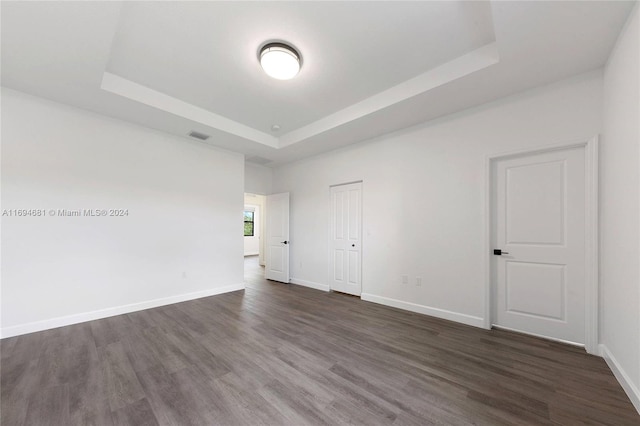 unfurnished room featuring a tray ceiling and dark hardwood / wood-style flooring