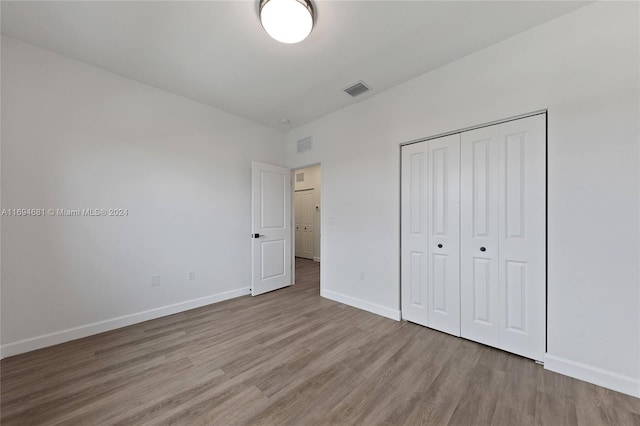 unfurnished bedroom featuring wood-type flooring and a closet