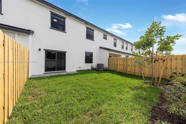 rear view of property featuring a lawn and central AC