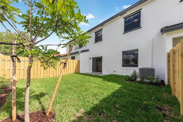 rear view of property featuring cooling unit and a lawn