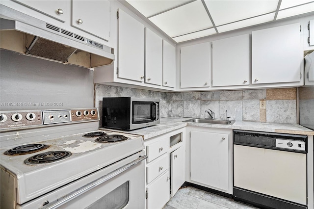 kitchen featuring a paneled ceiling, white appliances, sink, light tile patterned floors, and white cabinetry