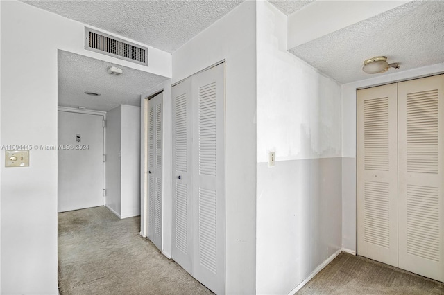 hallway with carpet and a textured ceiling