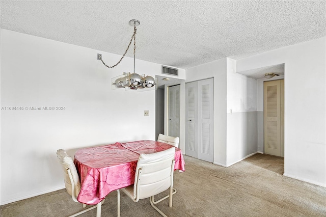 dining space featuring carpet floors, a chandelier, and a textured ceiling