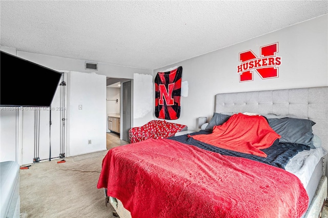 carpeted bedroom with a textured ceiling and connected bathroom