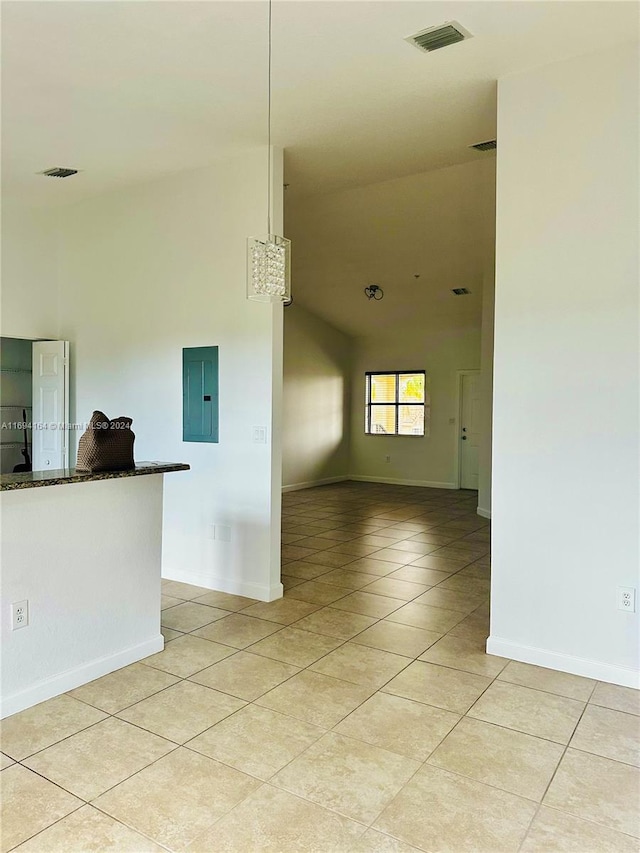 unfurnished room featuring high vaulted ceiling, light tile patterned floors, and electric panel