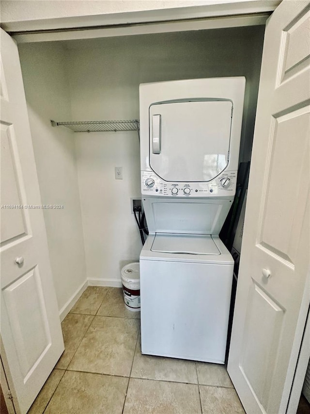 clothes washing area featuring light tile patterned floors and stacked washing maching and dryer