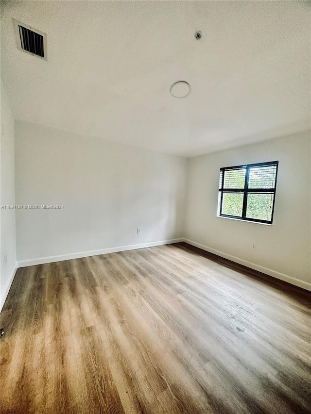 empty room featuring wood-type flooring and a textured ceiling