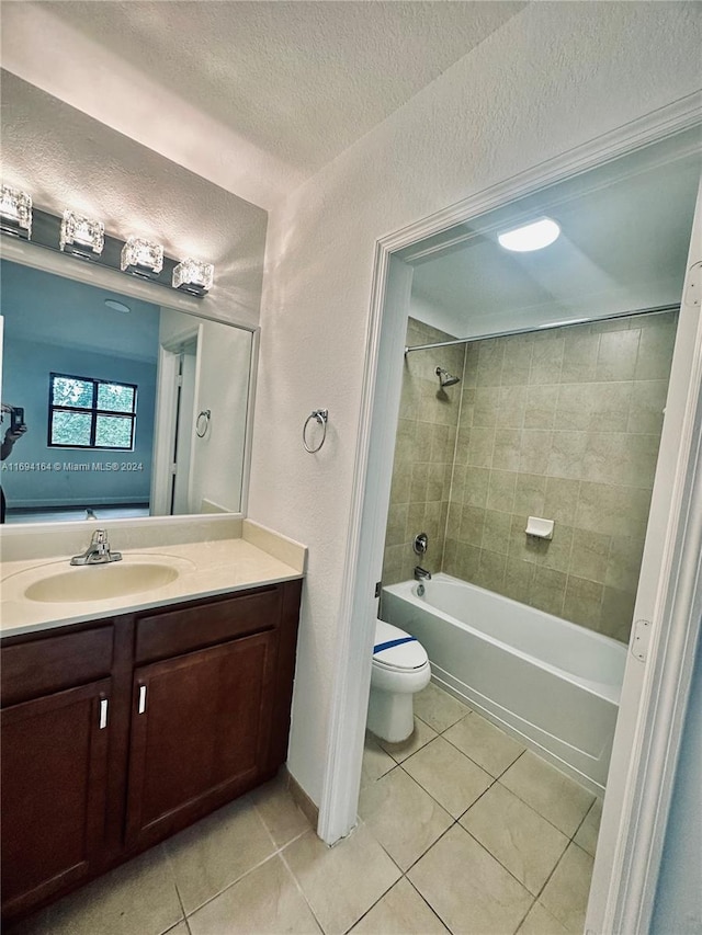 full bathroom featuring vanity, tiled shower / bath, tile patterned flooring, toilet, and a textured ceiling