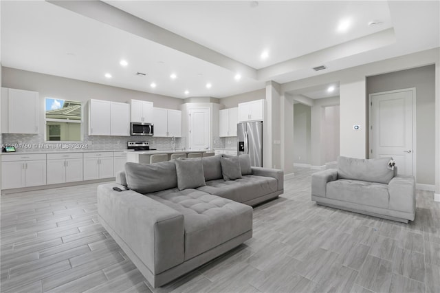 living room with light hardwood / wood-style floors and a raised ceiling