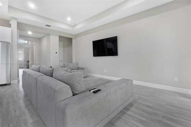 living room featuring light wood-type flooring and a tray ceiling