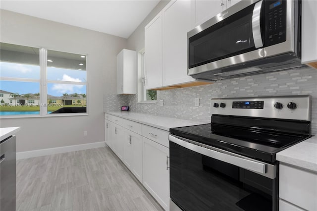 kitchen with white cabinets, decorative backsplash, appliances with stainless steel finishes, and light hardwood / wood-style flooring