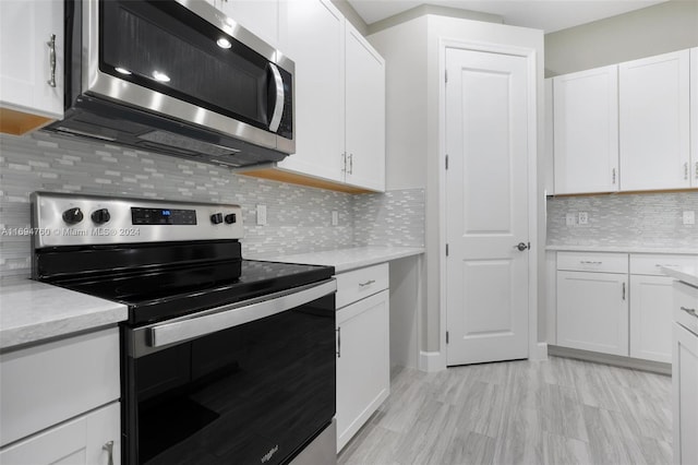 kitchen featuring white cabinets, appliances with stainless steel finishes, tasteful backsplash, and light stone countertops