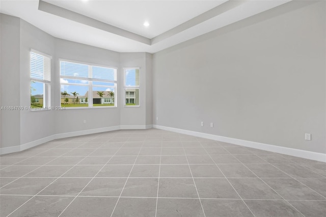 tiled spare room featuring a tray ceiling