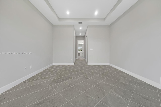 empty room featuring a tray ceiling and tile patterned floors