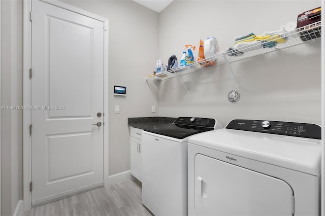 clothes washing area with washer and clothes dryer, cabinets, and light wood-type flooring