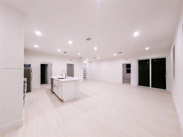 kitchen featuring white cabinets, appliances with stainless steel finishes, sink, and a center island with sink