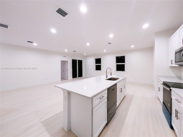 kitchen with electric stove, sink, black dishwasher, a kitchen island with sink, and white cabinets