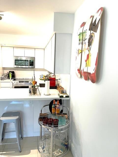 kitchen featuring white cabinets, stainless steel appliances, and light tile patterned floors