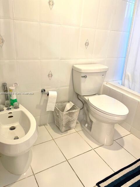 bathroom with shower / bath combo, tile patterned flooring, a bidet, toilet, and tile walls