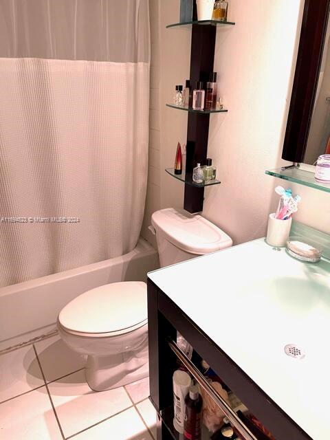 bathroom featuring tile patterned flooring, shower / tub combo with curtain, and toilet