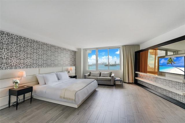 1100 W Ave Unit 918, Miami Beach, FL 33139 - bedroom featuring wallpapered walls, wood finished floors, and an accent wall