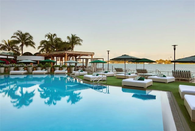 pool at dusk featuring a water view