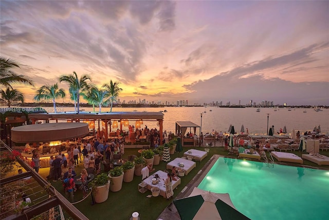 pool at dusk featuring a water view