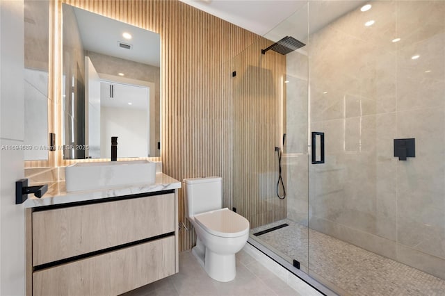 bathroom with a shower with door, vanity, tile patterned floors, and toilet