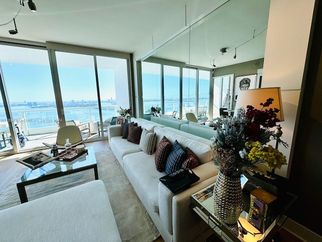 living room featuring a water view, floor to ceiling windows, and hardwood / wood-style flooring