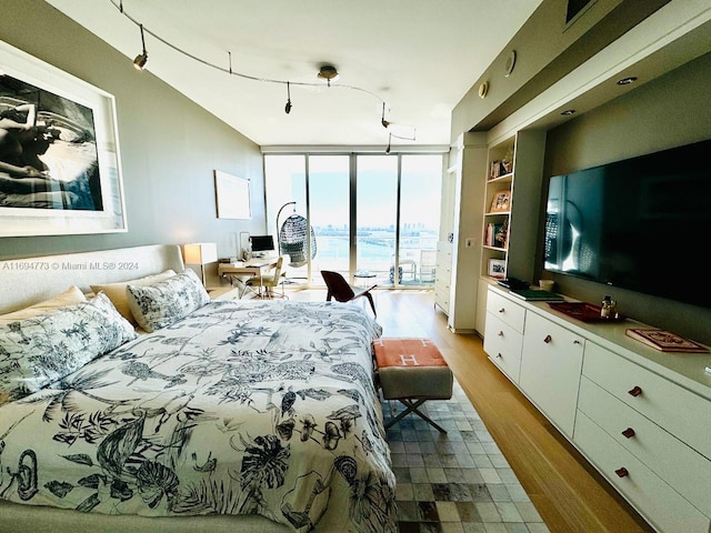 bedroom featuring hardwood / wood-style floors, a wall of windows, and access to outside