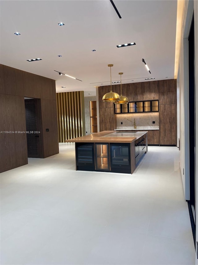 kitchen with dark brown cabinets, a center island, hanging light fixtures, and wooden walls